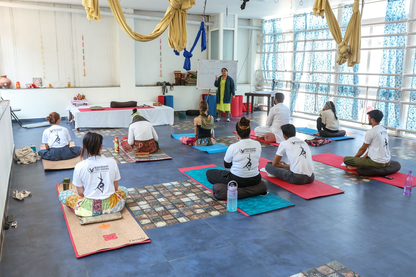 Group of adults attending a yoga class in a spacious, modern studio with an instructor.